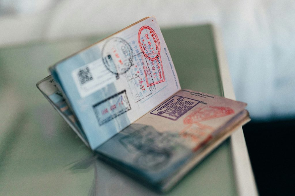 Indian navy blue passport on a wooden table next to a smartphone showing the Passport Seva online portal