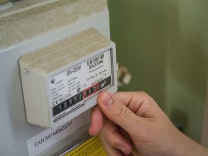 Indian electricity meter on a wall next to a monthly power bill showing high units consumed