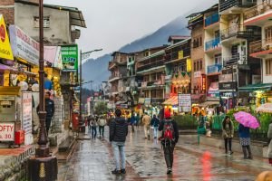 Snow-covered Manali mountain valley with wooden guesthouses and pine trees in winter