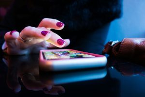 Indian person scrolling through apps on a smartphone with popular app icons visible on screen