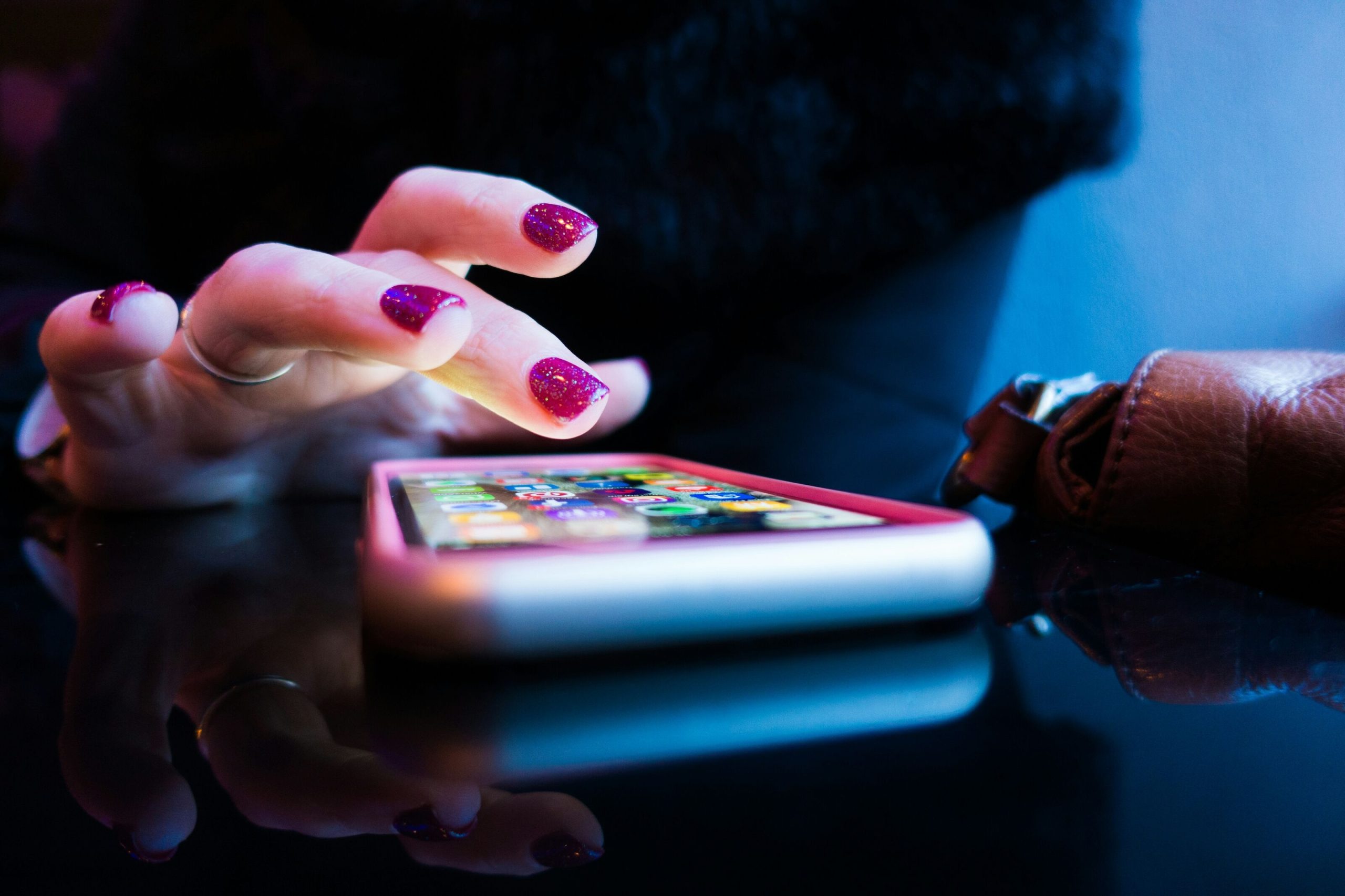 Indian person scrolling through apps on a smartphone with popular app icons visible on screen
